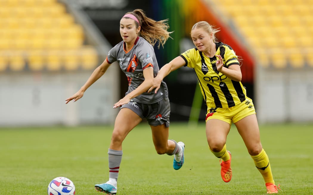 Grace Wisnewski of the Phoenix battles for possession with Brisbane Roar's Shea Connors.