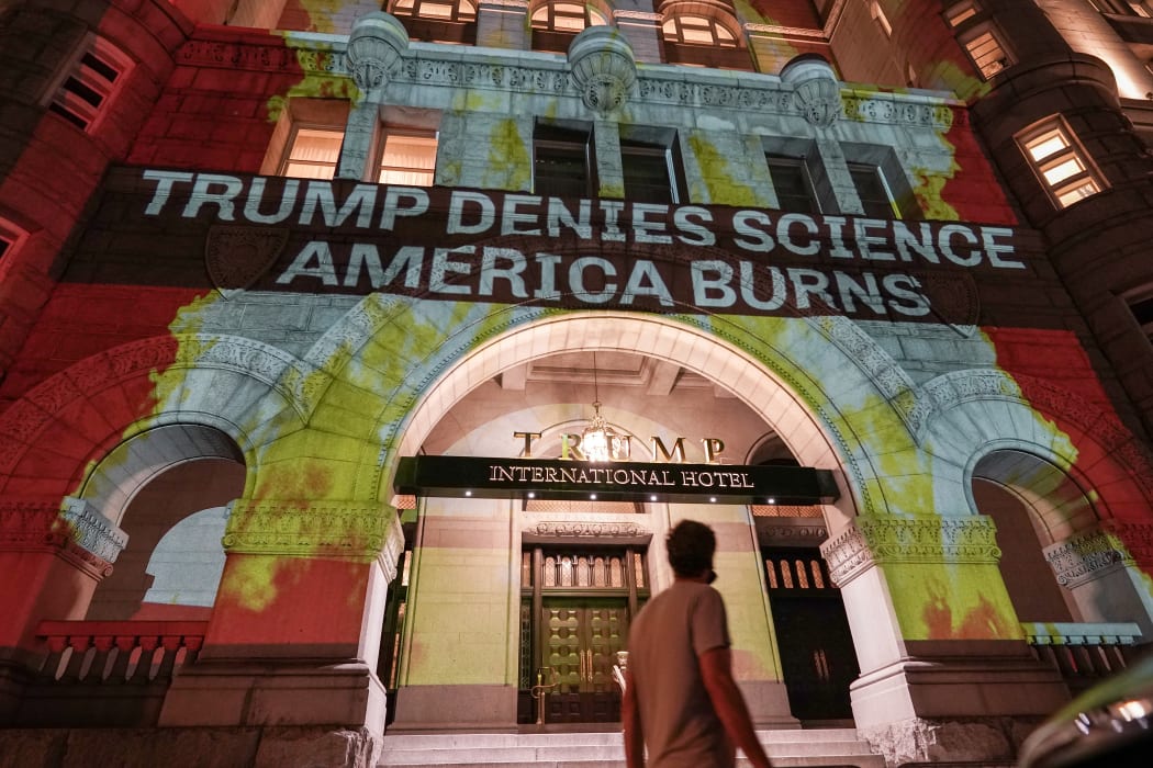 Activists project flames and commentary on the side of the Trump International Hotel in protest of President Donald Trump's response to science and climate change.
