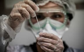 (FILES) In this file photo taken on September 22, 2020 A medical assistant takes a sample from a patient for a coronavirus (Covid-19) test at an analysis laboratory in Le Peage-de-Roussillon, some 30kms south of Lyon, south-eastern France.