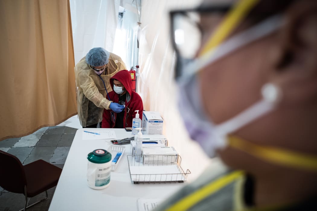 A doctor examines a patient for a COVID-19 test inside a testing tent in New York.