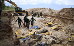 Indonesian soldiers bury quake victims in a mass grave in Poboya after an earthquake and tsunami hit the area on 28 September.