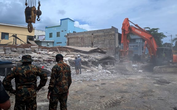 Rescue workers are seen at the site of a collapsed building after an earthquake struck Port Vila, the capital city of Vanuatu, on December 18, 2024. - Rescue teams dug for survivors trapped in crumpled buildings in the Pacific nation of Vanuatu on December 18 after a powerful earthquake killed at least 14 people, some of them buried in rubble and landslides. (Photo by AFP)