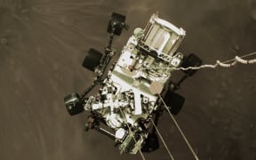 This photo released by NASA, shows the Perseverance rover being lowered by the Sky Crane to the surface of Mars on February 18, 2021. - NASA said February 18, 2021 that the Perseverance rover has touched down on the surface of Mars