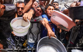 Palestinians shove to get a portion of cooked food from a charity kitchen in Jabalia in the northern Gaza Strip on 17 May, 2025. The humanitarian crisis in the besieged Gaza Strip has worsened significantly since Israel blocked all aid from entering the territory on March 2, days before resuming its military offensive following a brief ceasefire.