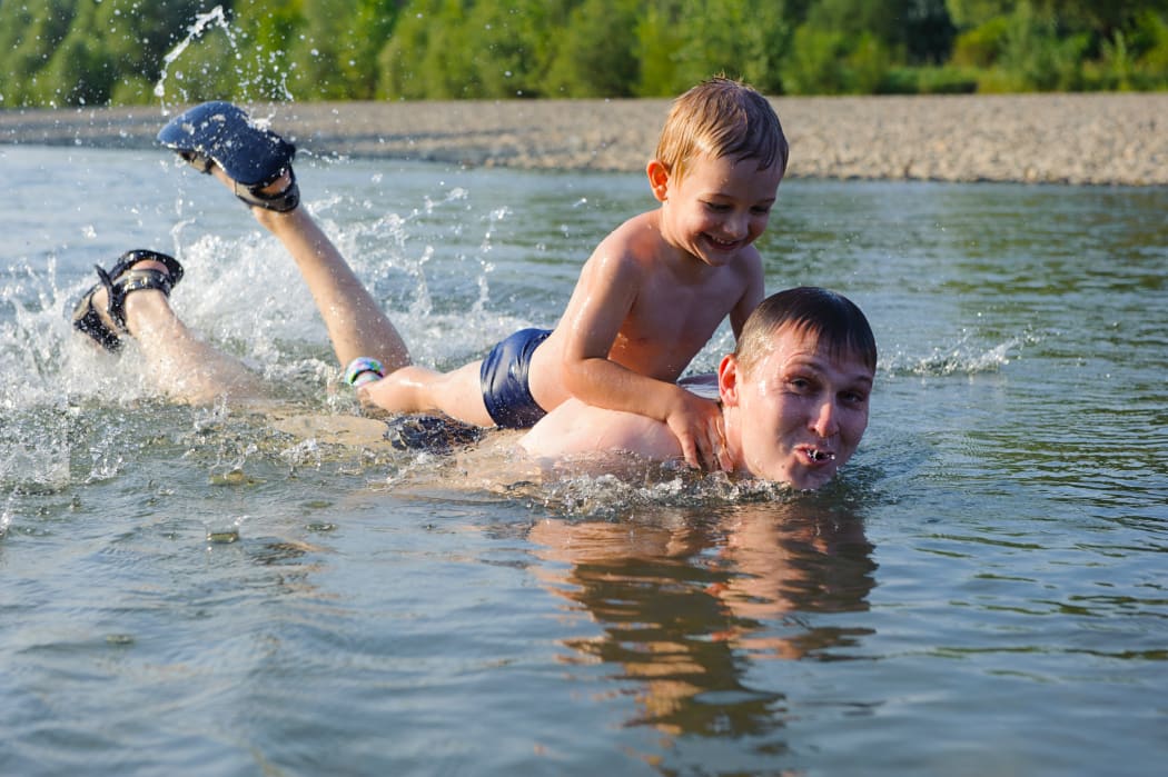 A father and his young son swim in a river (file)