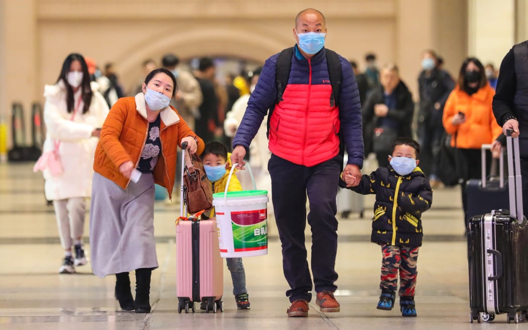 Commuters wearing face masks walk in Hankou railway station in Wuhan, in China's central Hubei province on January 21, 2020.