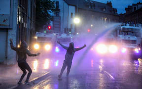 Riot Police use a water cannon in an attempt to disperse protestors gathered for a thrid night of anti-immigration demonstrations, in Ballymena, Northern Ireland, on June 11, 2025. Police were braced late Wednesday for a third night of violence in a riot-hit town in Northern Ireland as hundreds gathered on the streets armed with molotov cocktails and unrest spread to other areas. The riots erupted after the arrest of two teenagers accused of attempting to rape a young girl. The pair appeared in court on Monday where they asked for a Romanian interpreter. (Photo by PAUL FAITH / AFP)