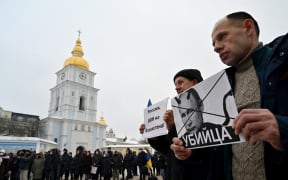 People hold placards depicting Russian president Vladimir Putin signed "Killer" and another one reading "Russia, go out from Kazakhstan!" during an action dubbed #SayNOtoPutin in Kyiv.