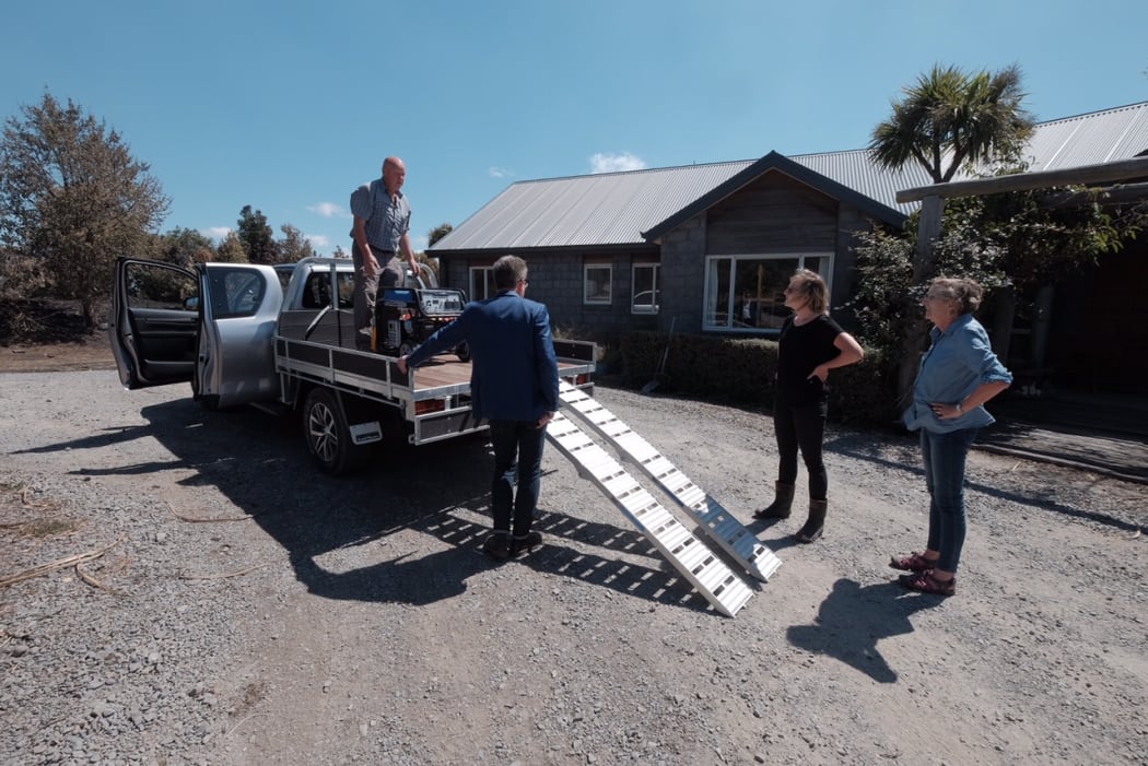 John Campbell speaks to the the McKenzie family whose house survived the fire, but property was destroyed
