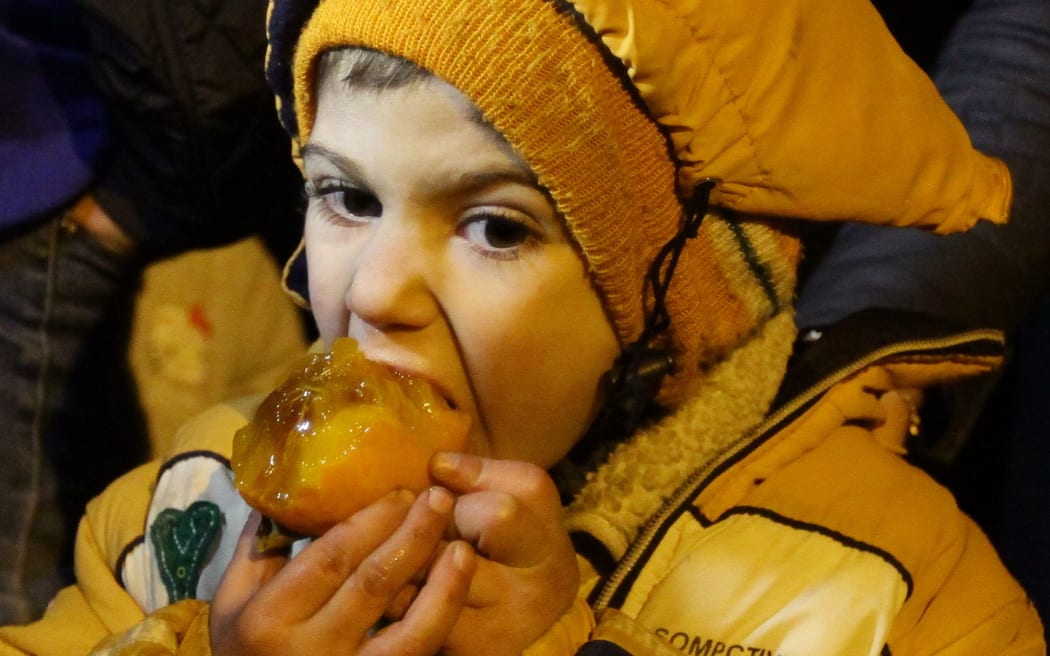 A Syrian child eats a fruit on the outskirts of the besieged rebel-held Syrian town of Madaya.