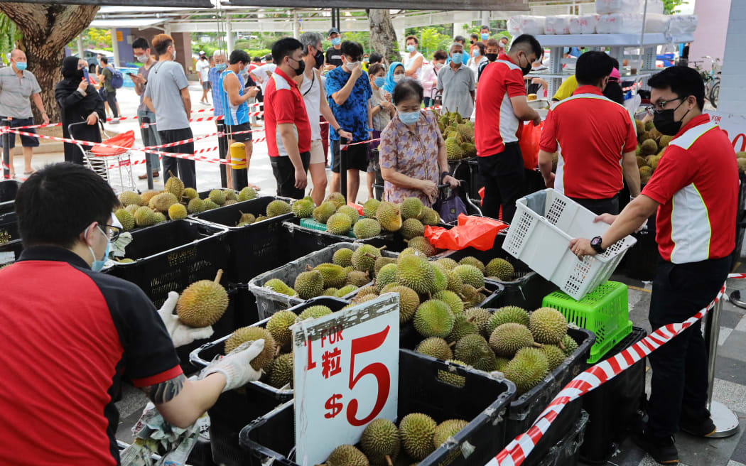 People wait in queue to buy durian on June 24, 2021 in Singapore. On June 21, Singapore entered into a calibrated easing of social management measures as local community COVID-19 cases remain under control.