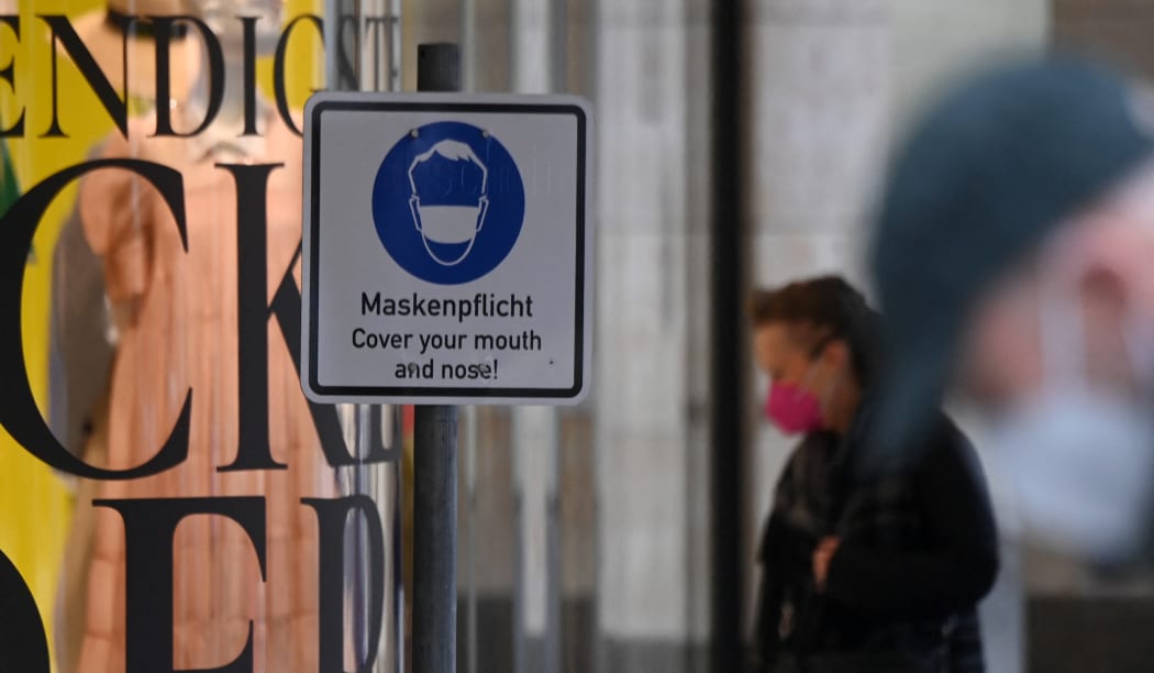 A pedestrian wearing face mask walks past a mask required sign Munich, southern Germany, on 23 March 2021.