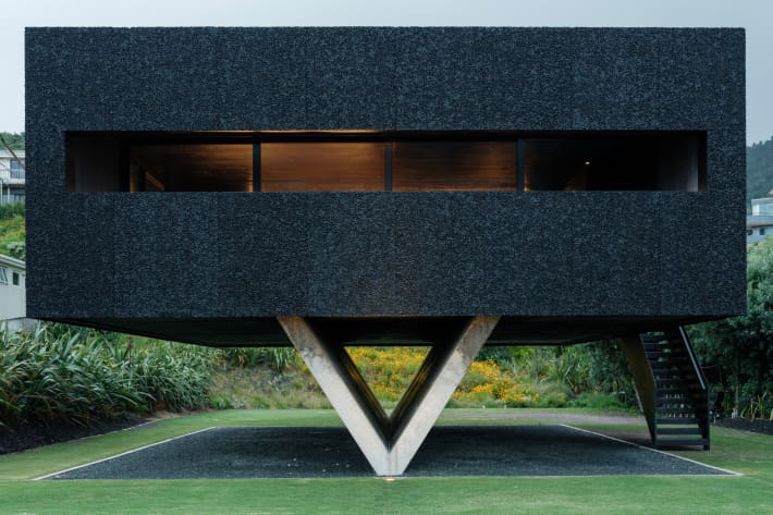 An image of a house installed on concrete V-shaped stilts in Piha.