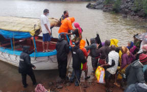 taken on July 23, 2021 shows National Disaster Response Force (NDRF) personnel rescuing stranded villagers from the low lying areas  in Ambewadi of Kolhapur district of Maharashtra.