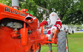 Santa waves hello on his big red tractor.