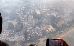 This handout video grab courtesy of Richard Olsten taken on August 9, 2023 shows smoke billowing from destroyed buildings in Lahaina as wildfires burn across Maui, Hawaii. At least six people have been killed in a wildfire that has razed a Hawaiian town, officials said Wednesday, as desperate residents jumped into the ocean in a bid to escape the fast-moving flames.