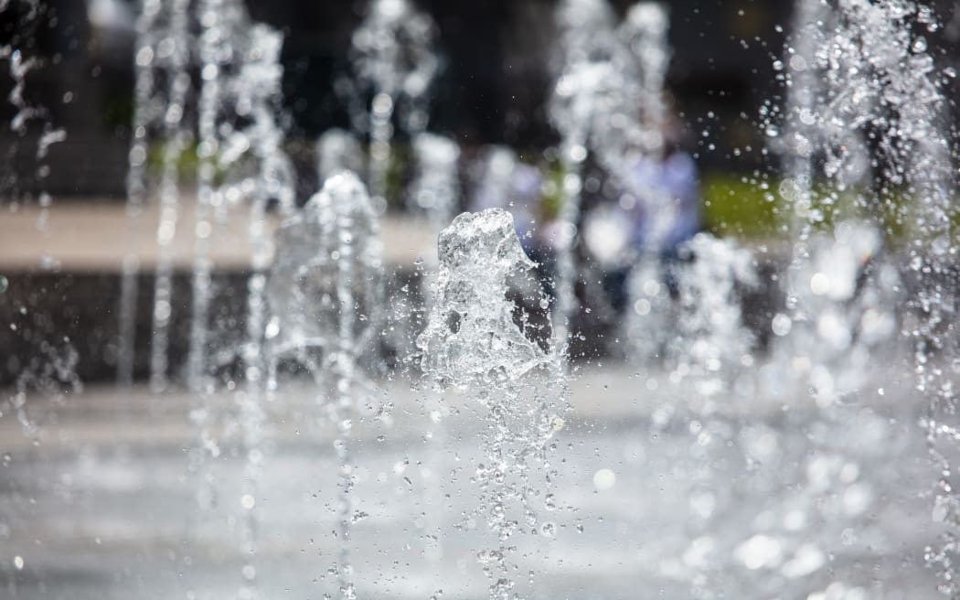 Splashing water from a fountain in the park as a background .
