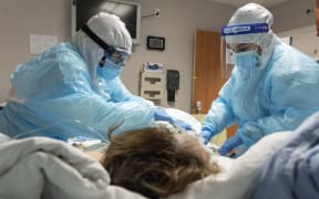 HOUSTON, TX - DECEMBER 10: (EDITORIAL USE ONLY) Medical staff members Diana Escalante, left, and Stephanie, right, clean a patient in the COVID-19 intensive care unit (ICU) at the United Memorial Medical Center on December 10, 2020 in Houston, Texas.