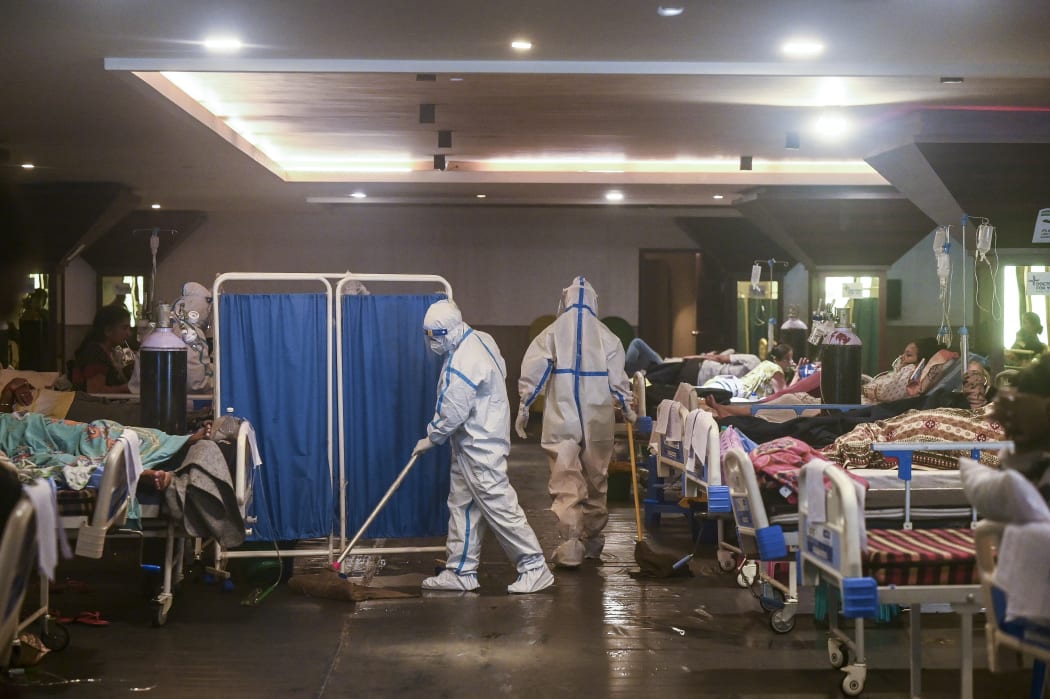 A health worker wearing a personal protective equipment suit cleans the floor inside a banquet hall temporarily converted into a Covid-19 coronavirus ward in New Delhi