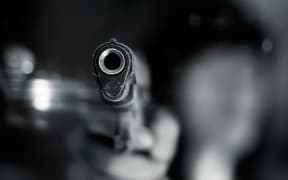 Black and white, woman pointing a old gun to front with one Hand on dark background