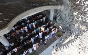 Palestinian Muslim worshippers attend friday prayers amidst the rubble of the destroyed Albaani Mosque in Khan Yunis in the southern Gaza Strip on October 17, 2025. Hamas said it was committed to the US-brokered agreement that halted its war with Israel, and to returning all the bodies of hostages still unaccounted for under the ruins of Gaza. (Photo by Omar AL-QATTAA / AFP)