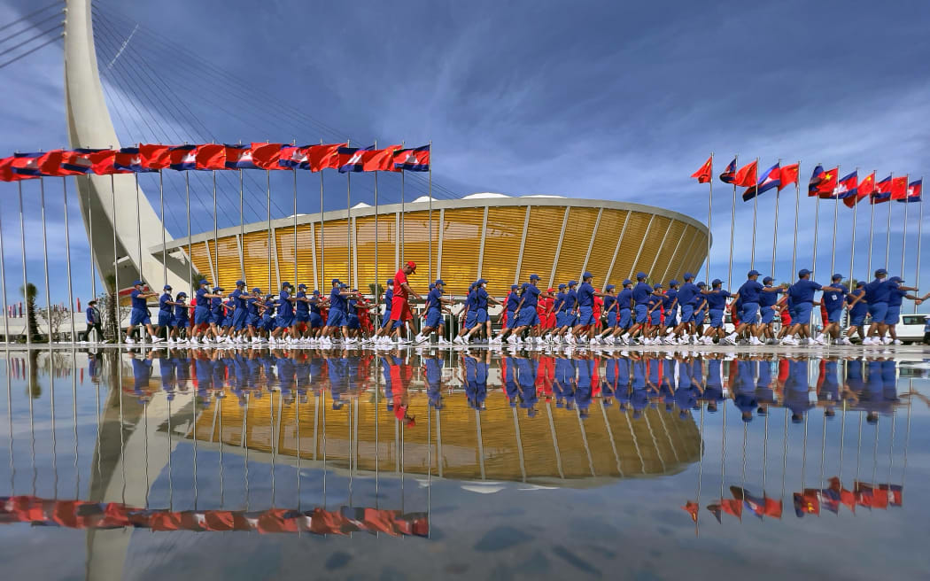 Participants march outside the premises for the opening ceremony of Cambodia's Morodok Techo National Stadium, funded by China's grant aid under its Belt and Road Initiative, in Phnom Penh on December 18, 2021.