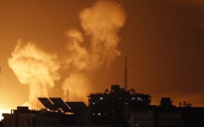 Smoke rises above buildings in Gaza City as Israel launches air strikes on the Palestinian enclave on late April 6, 2023. - Several explosions coming from Gaza were heard by AFP journalists on April 6, 2023, night, as the Israeli army said it was carrying out strikes in the area. The Israeli army "is currently striking in the Gaza Strip," read an army statement shortly after AFP heard at least three explosions. A Palestinian security source said the strikes had hit several Hamas training sites. (Photo by MOHAMMED ABED / AFP)