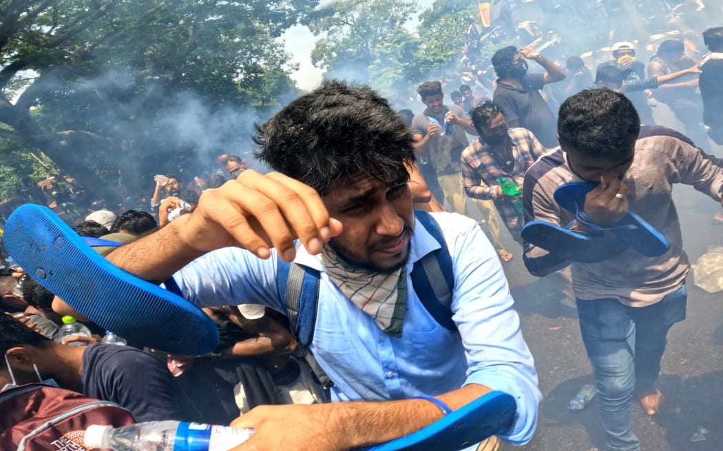 Sri Lankan anti-government protesters run away from tear gas during a protest that resulted in protesters occupying the prime minister's office at Colombo, Sri Lanka. 13 July 2022 (Photo by Tharaka Basnayaka/NurPhoto) (Photo by Tharaka Basnayaka / NurPhoto / NurPhoto via AFP)