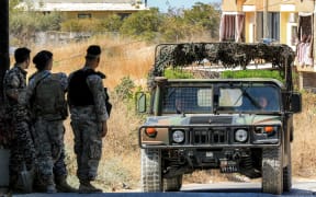 A Lebanese army vehicle approaches soldiers stationed near the Ain al-Hilweh camp for Palestinian refugees in Lebanon's southern city of Sidon on September 13, 2025, as armed Palestinian groups hand over their weapons to Lebanese authorities. Palestinian factions handed over weapons from Lebanon's largest refugee camp on September 13, an official from the Palestine Liberation Organisation (PLO) said, as part of a push by the government to disarm non-state groups. (Photo by MAHMOUD ZAYYAT / AFP)