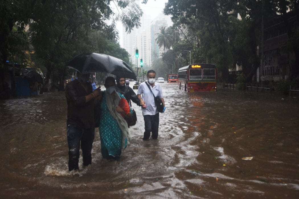 People walking on a flooded road as Cyclone Tauktae brings heavy rain to  Mumbai on 17 May 2021.