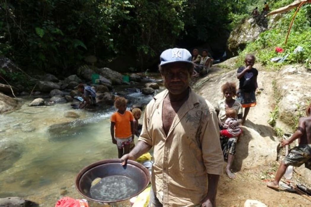 A man from Nusuta village showing the gold produced from two to three hours work at the Charivunga river near pit 4, also known as Dawsons. He estimates that there are seven to eight grams of gold in his pan. He produced this with the help of his wife and children.