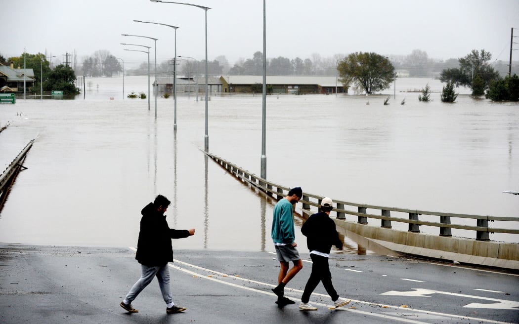 People walk over an old Windsor Bridge along the overflowing Hawkesbury River in the northwestern Sydney suburb of Windsor on 6 July, 2022.
