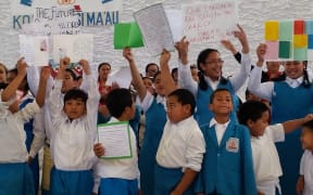 Students and parents hold signs urging the education minister to reverse a suspension of the school's license.