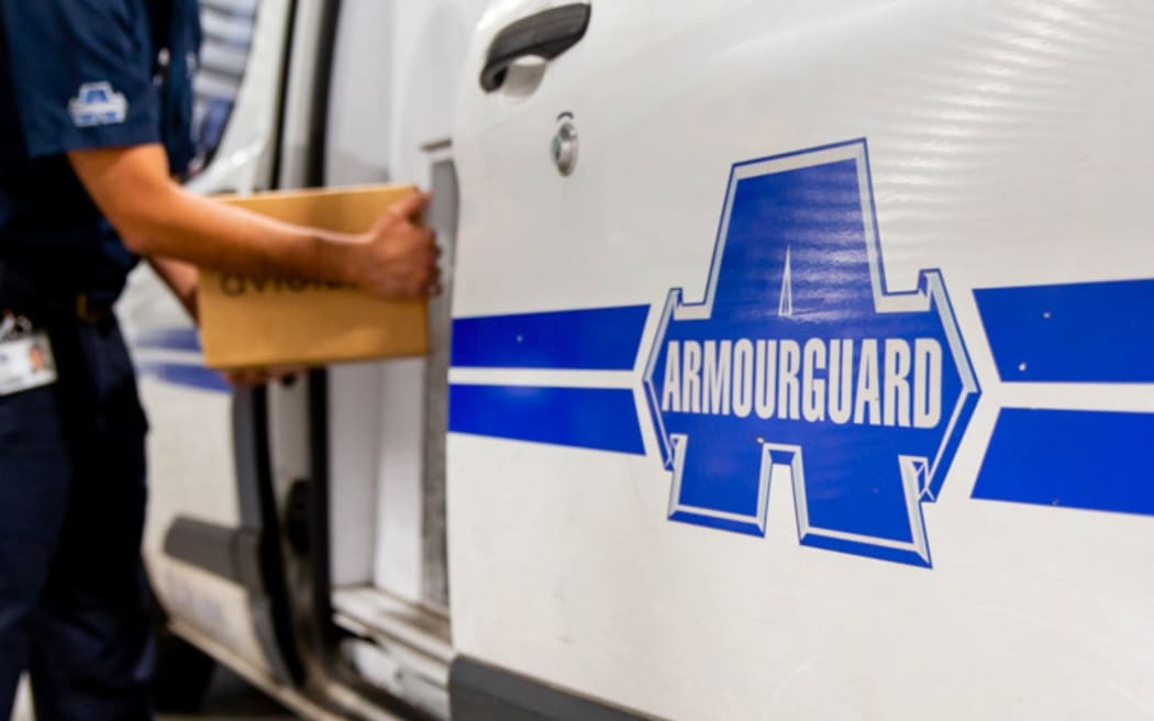 A man loads boxes onto an Armourguard truck.