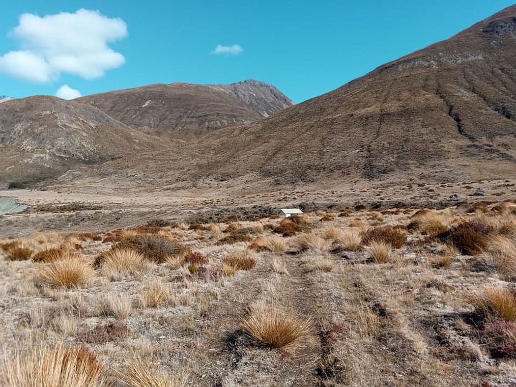 A view of a South and mountain range with a small hut nested at its base.