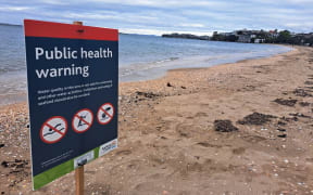 A public health warning sign at Mission Bay beach alert people to not swim, fish or collect shellfish.