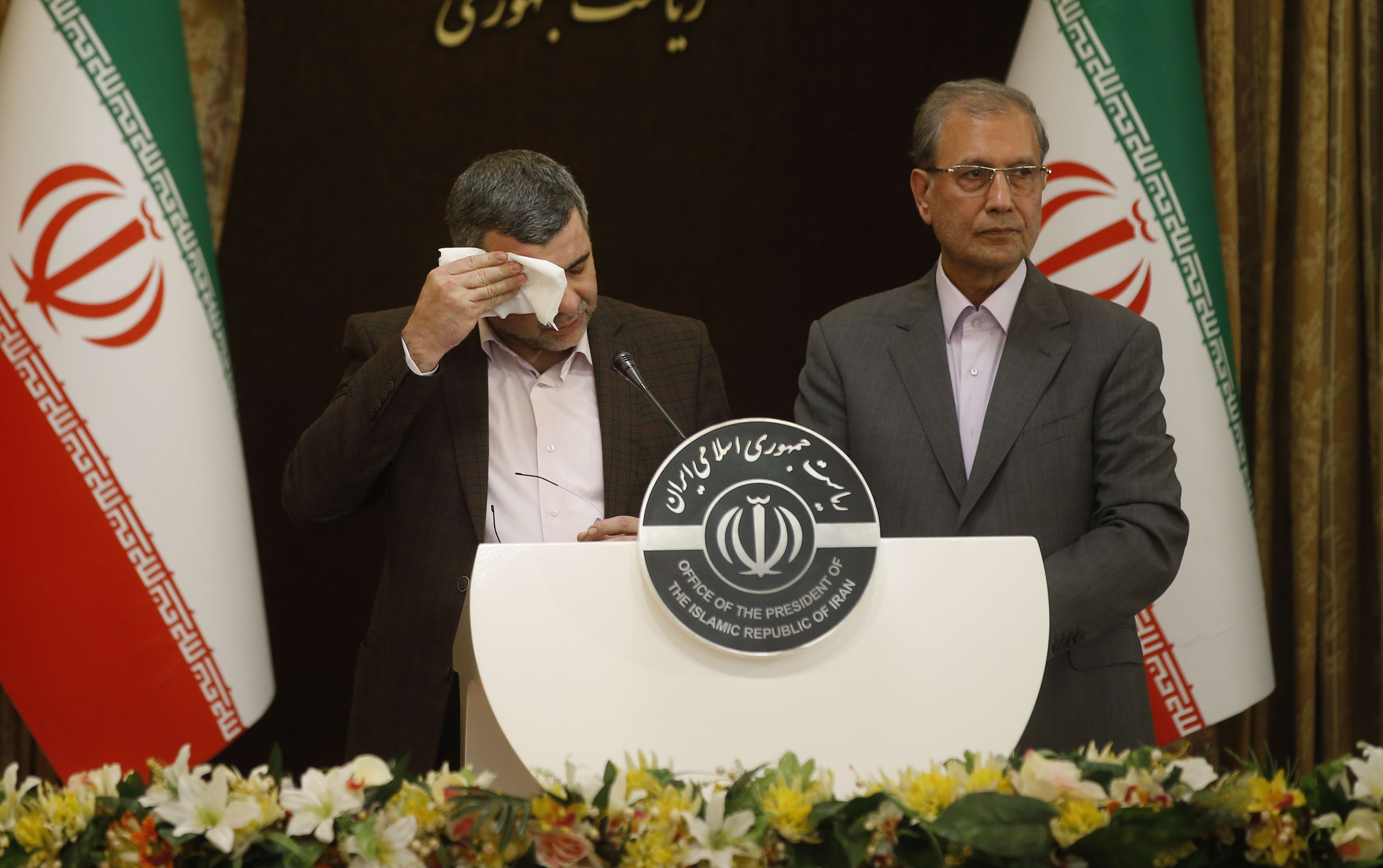Iranian Deputy Health Minister Iraj Harirchi, left, wipes his brow during a media conference.