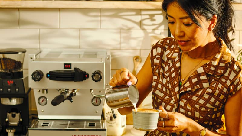 An image from Celeste Wong's book, Coffee Creations: 90 delicious recipes for the perfect cup. Celeste Wong pours milk into her coffee cup to make a flat white.