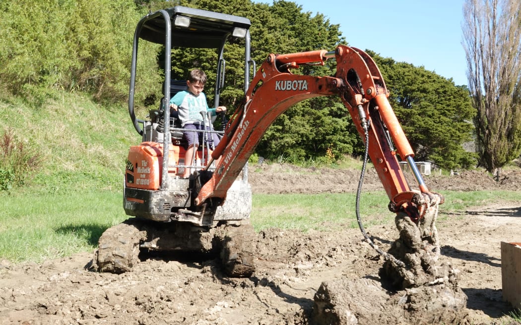 James Harold's son Axel, 7, has a go at clearing silt from their Wimbledon property.