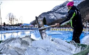 Event staff break up ice which covered the competition pool