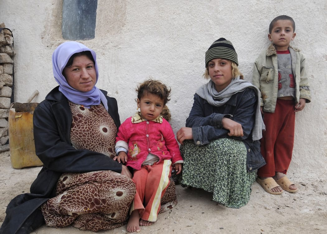 An Iraqi woman and her family sit outside their farm house near the Sinjar mountains in northern Iraq.