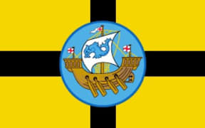 A yellow flag with a black cross and a picture of a ship with a dolphin on the sail.