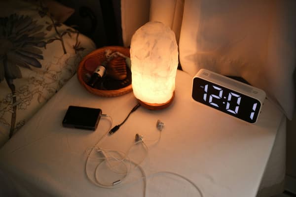 Alarm clock, lamp and wires on bedside table.