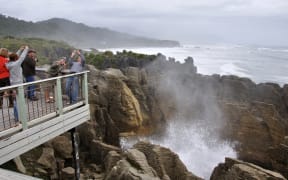 PUNAKAIKI, NEW ZEALAND, MAY 5, 2010: Tourists photograph themselves while the main blowhole is in action at the Pancake Rocks, Punakaiki, West Coast, South Island, New Zealand