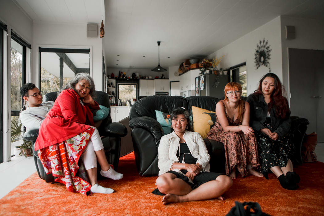 (L-R) Tom, Eva, Avi, Cinta and Cindy sit in the living room of Avi's house in Avi outside her home in Tutukākā
