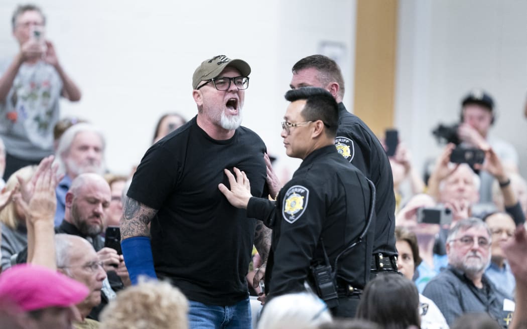 ASHEVILLE, NORTH CAROLINA - MARCH 13: A man shouts at Rep. Chuck Edwards (R-NC) as members of law enforcement escort him out of the buiding during a congressional town hall meeting on March 13, 2025 in Asheville, North Carolina. The event comes as Republicans have faced protestors at town halls critical of the Trump administration slashing federal jobs.   Sean Rayford/Getty Images/AFP (Photo by Sean Rayford / GETTY IMAGES NORTH AMERICA / Getty Images via AFP)