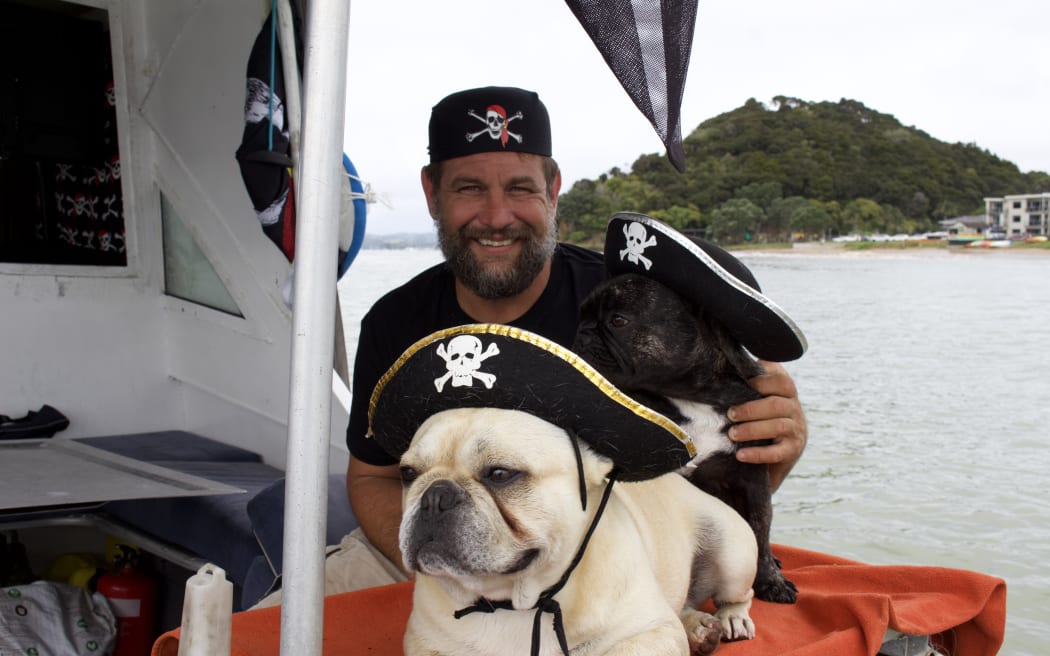Dylan Bacher and his two dogs, Bosco (front) and Treasure (back) live on his 'boat whare' in Paihia, Te Tai Tokerau.