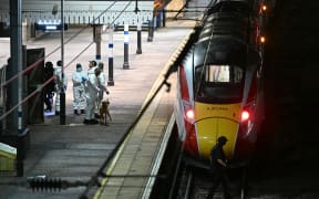 Police officers and a dog handler work on the platform alongside an LNER Azuma train at Huntingdon Station in Huntingdon, eastern England, on 1 November, 2025, following a stabbing on a train.
