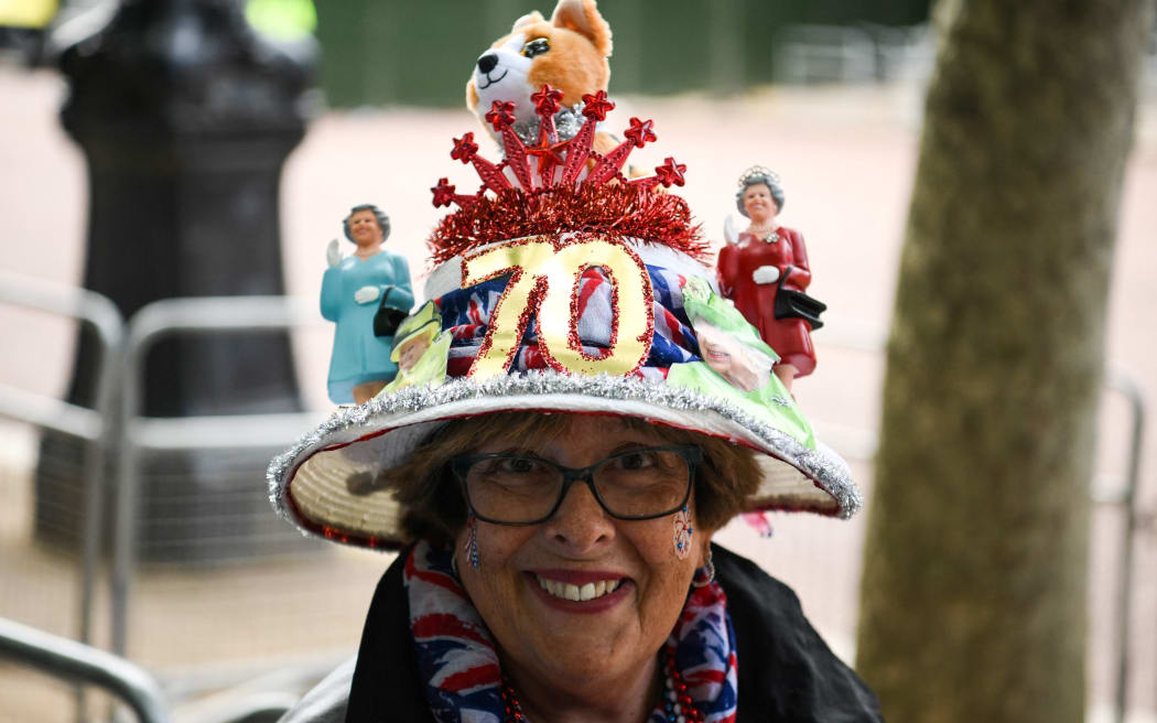 A woman wearing a decorated hat poses on The Mall, in London, on June 1, 2022 ahead of the Platinum Jubilee's celebrations for Britain's Queen. - Britain's Queen Elizabeth II has been on the throne since she was 25, an ever-present figure for the lives of most people in Britain, as well as one of the most recognisable people around the world. She will celebrate her Platinum Jubilee over four days from Thursday June 2nd, for her 70 years of reign. (Photo by Daniel LEAL / AFP)