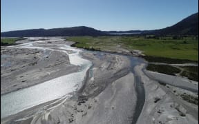 A view of the lower Wanganui River in South Westland showing the line of silt and debris left from where the river broke breached a stop bank and flowed across farmland towards Lake Ianthe, in the distance. Much of that farmland is reclaimed riverbed.